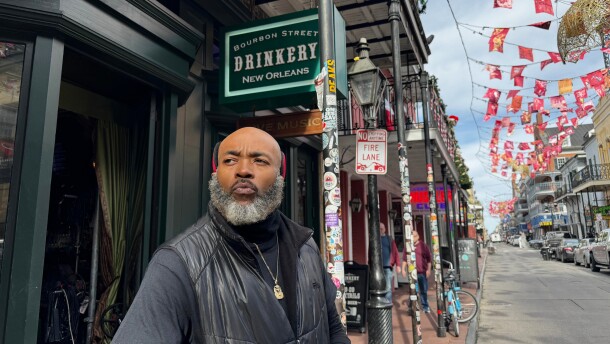 Miguel Thornton stands under memorial flags for the victims of a Jan. 1, 2025, vehicle ramming attack, outside of the Bourbon Street bar, where he works, on Monday, Dec. 29, 2025, in New Orleans. (AP Photo/Jack Brook)