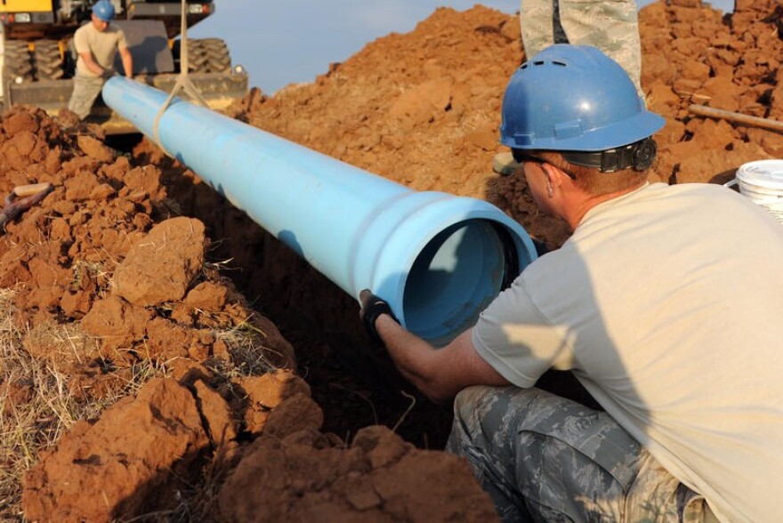 Airmen at Altus Air Force Base in Oklahoma install a water pipe behind a tanker fuel yard, 2012 (U.S. Air Force)