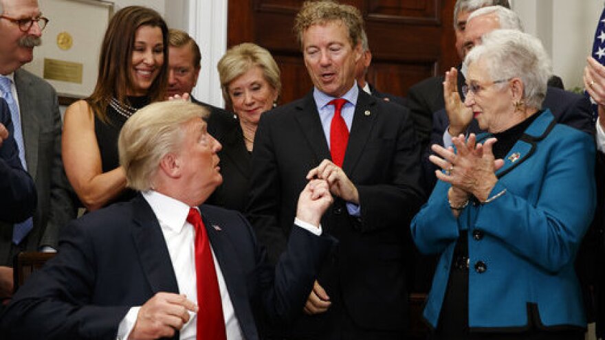 President Trump hands a pen that he used to sign an executive order on health care to Sen. Rand Paul, R-Ky., in the Roosevelt Room of the White House on Thursday.