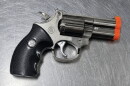A cigarette lighter that look like a handgun with a black handle and silver barrel.