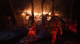 Firefighters move away from a burning house after discovering downed live power lines, as the Thomas wildfire continues to burn in Carpinteria, Calif., on Dec. 10, 2017. (Mark Ralston/AFP/Getty Images)