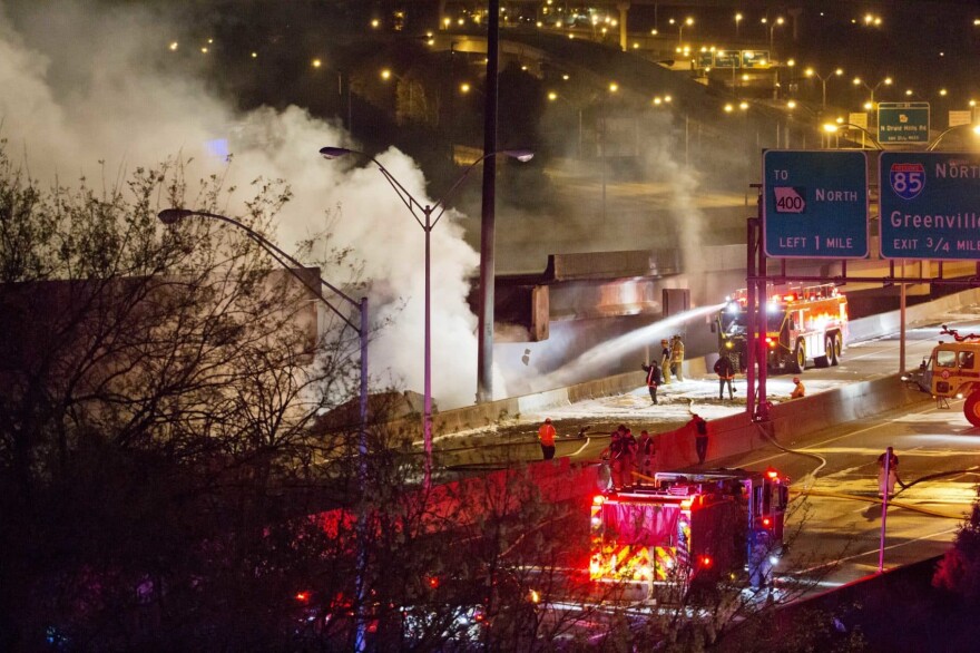 In this Thursday, March 30, 2017 file photo, smoke billows from a section of an overpass that collapsed from a large fire on Interstate 85 in Atlanta. Georgia officials say repairing damaged sections of I-85 north of downtown Atlanta will take months. Three people were arrested in connection with the fire Friday evening, March 31, and officials suspect one of them of setting it. (David Goldman, File/AP)