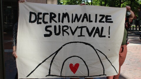 Protestors gathered outside city hall and held signs like this, ahead of the vote to strike city ordinance 130.13B. They argue the move criminalizes homelessness as those who would be in danger of violating the ordinance are those who are homeless. Violators can be fined up to $250 by Manchester police.
