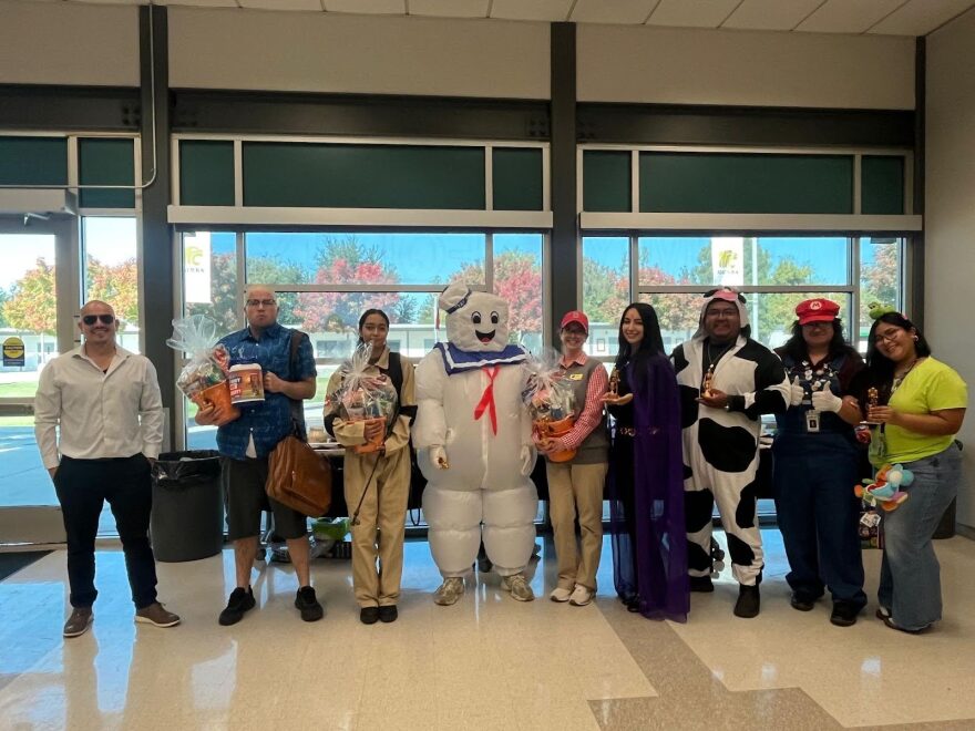 Staff and administrators, including Angel Reyna, left, and Cory Burkarth, second from left, pose in their costumes during the party.