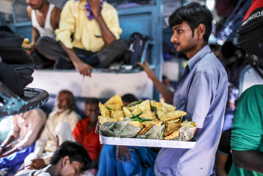 A vendor sells fried snacks on a train in northern India. Food vendors are a regular presence on most trains, jumping on and off trains at various stations, offering passengers a welcome snack break during their long journeys.