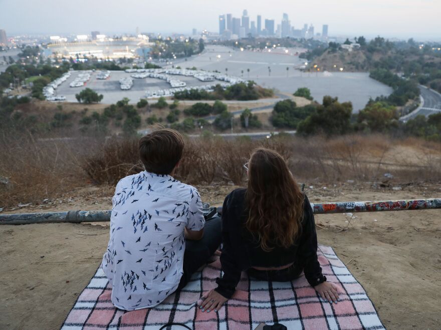 People gather for a picnic on a hillside overlooking Dodger Stadium in Los Angeles during a game Saturday. Spectators are currently not allowed to attend Major League Baseball games in order to prevent the spread of the coronavirus.