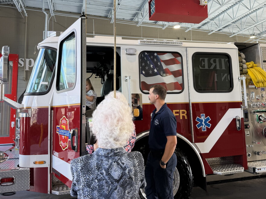 Lisa Frucht and her family watch as Frucht’s granddaughter sits inside Gainesville Fire Rescue’s new Engine 1. Frucht said her granddaughter is described as quiet, but not when it comes to fire engines. (Genesis Trujillo/WUFT News)