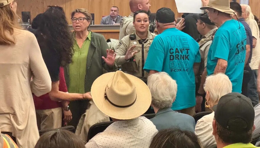 Sheriff Kim Stewart, at left, and a deputy, center, try to ease tensions during the Doña Ana County Commission meeting Tuesday, where public comments once again focused on the Project Jupiter data center project in Santa Teresa.