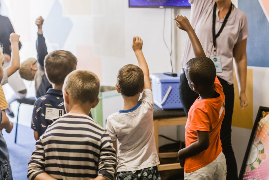 Children raising their hands in class. 