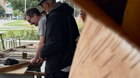 Ron J. Paquin framed by birch looking over the canoe build