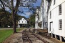 A railroad track curves by several white, wooden buildings.