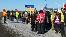 Bus workers wave signs on the strike line outside the Durham School Services bus barn on March 2, 2026.