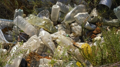 Plastic bottles and other garbage are seen next to a beach.