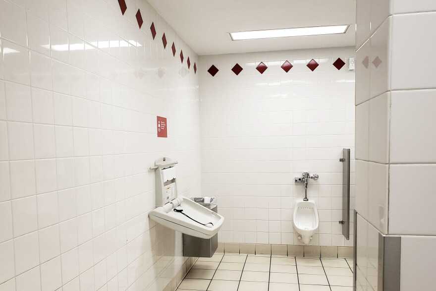 A diaper-changing station in a men's restroom.