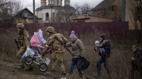 Ukrainian soldiers help a fleeing family crossing the Irpin river in the outskirts of Kyiv, Ukraine, Saturday, March 5, 2022. (Emilio Morenatti/AP)