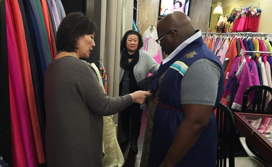 Youjung Jung measures Berris Anderson for a hanbok as his wife Lysa watches.