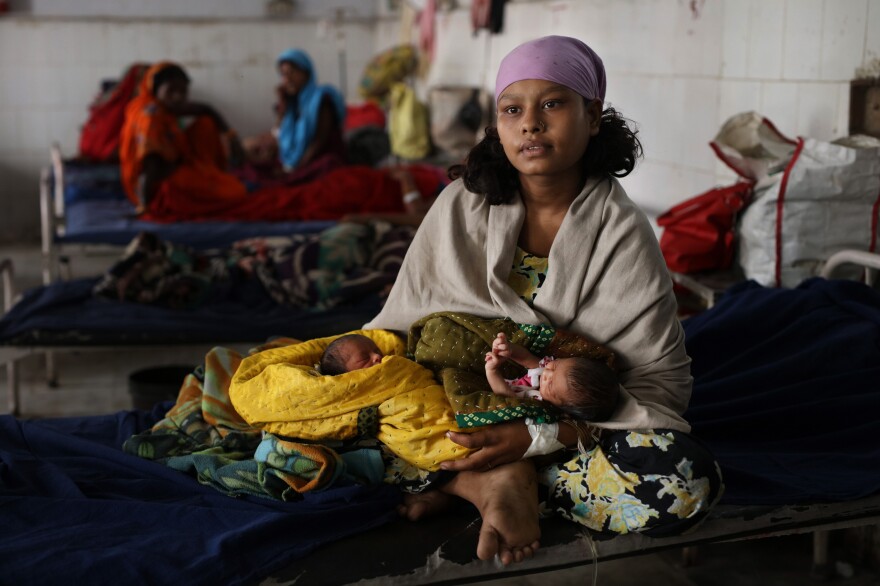 A mother holds her newborn twins at a Sri Krishna Medical College and Hospital, a public health facility in India.