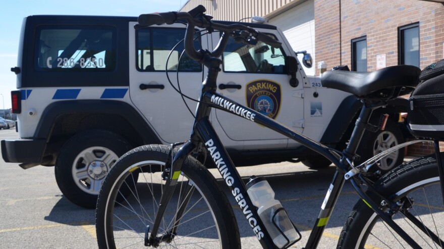 A white parking enforcement vehicle and a bike that reads "Parking Services" are parked next to each other in a parking lot.