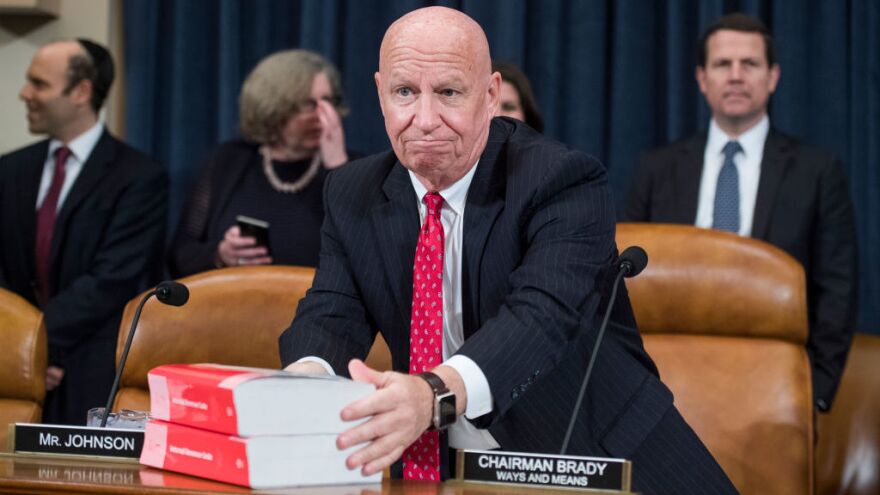 House Ways and Means Committee Chairman Kevin Brady, R-Texas, places books of the current tax code on the dais during Monday's markup of the Republicans' tax overhaul plan.