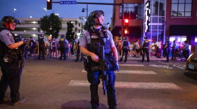 A police officer holds a firearm as community members gather on June 6 in Minneapolis, for Winston Boogie Smith Jr., who was fatally shot by members of a U.S. Marshals task force several days earlier. (Christian Monterrosa/AP Photo)