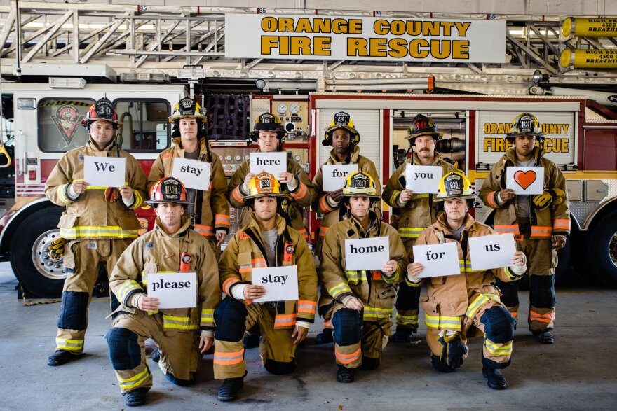 Orange County firefighters hold up signs that read "We stay here for you, please stay home for us."