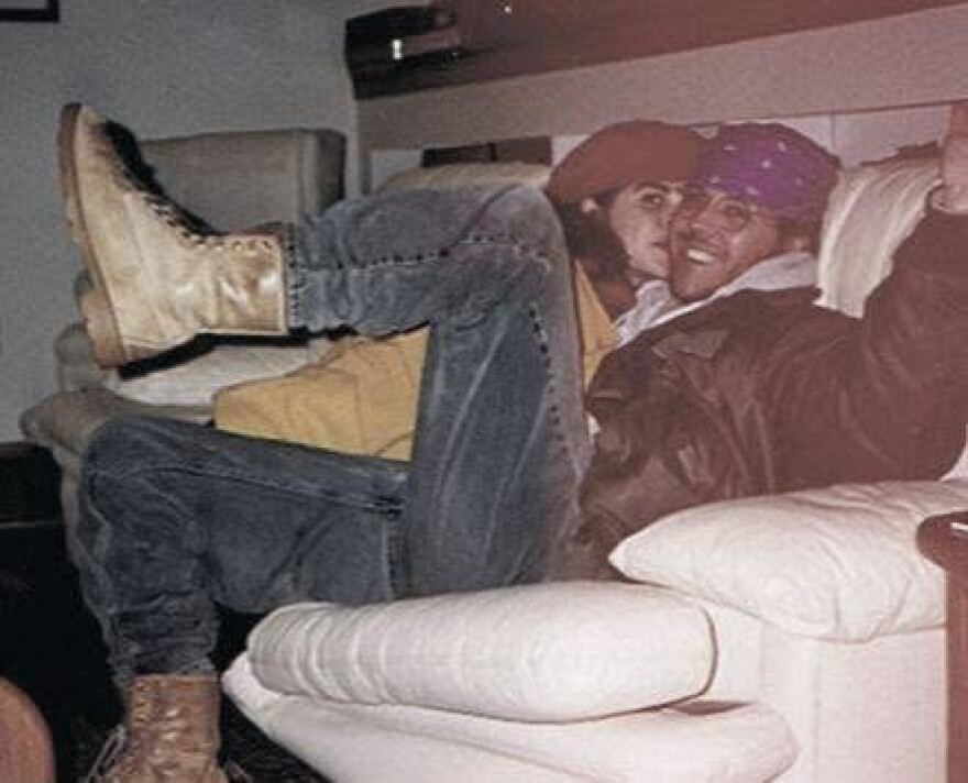 A man and a woman cuddle up on a couch together.