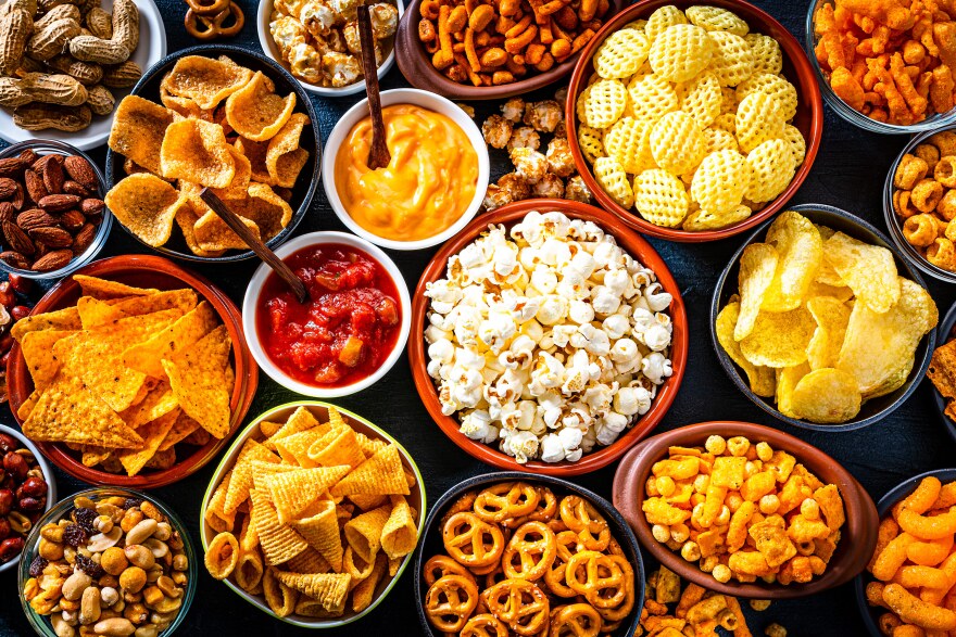 An assortment of salty snacks in bowls, as seen from above.