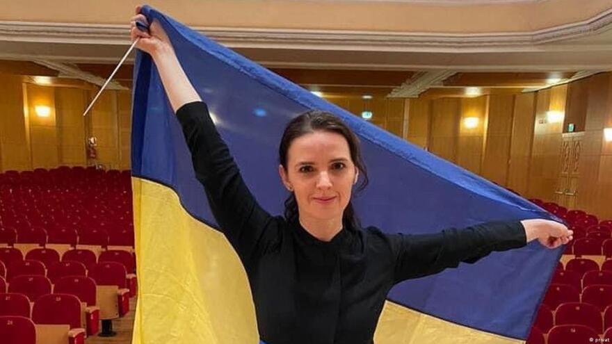 Conductor Oksana Lyniv holds up a Ukrainian flag over her head