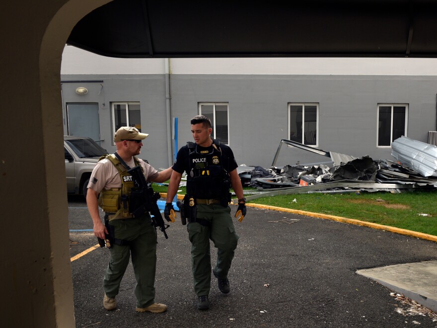 The U.S. Disaster Medical Assistance Team (DMAT) inspects a damaged hospital in Aguadillo, Puerto Rico, with a federal agent providing force protection.