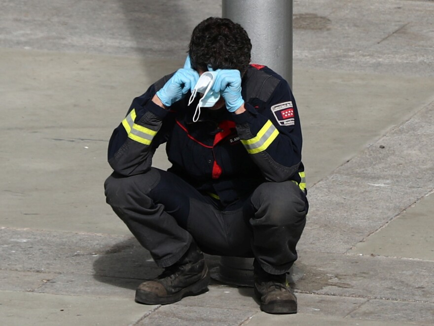 A firefighter takes a moment to rest outside a temporary hospital in a conference center in Madrid, Spain, that was set up as an overflow area for COVID-19 patients. More than a million coronavirus cases are now reported worldwide, putting intense pressure on health and emergency workers.