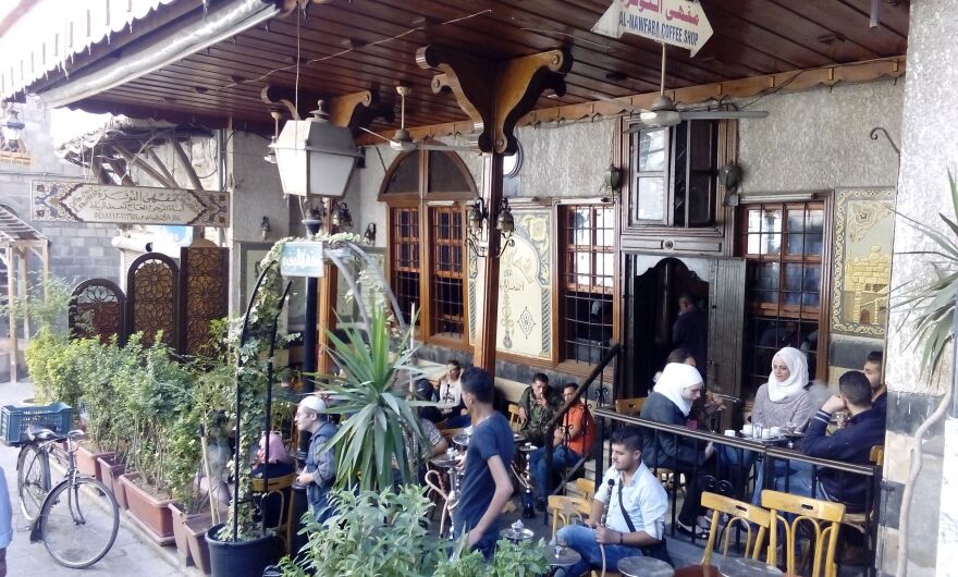 A cafe does a brisk business in Damascus. The city has suffered less damage and the economy still functions compared with many other parts of the ravaged counry.