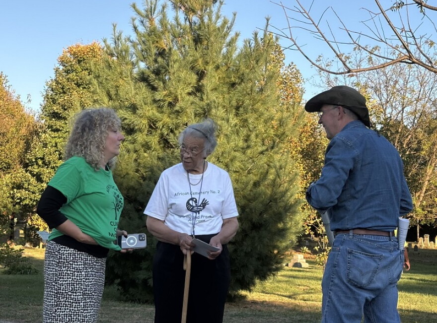 Co-founder of the Kentucky Climate Choir, Rosie Moosnick talks with historian Yvonne Giles and Mark Coyne, chair of African Cemetery #2.
