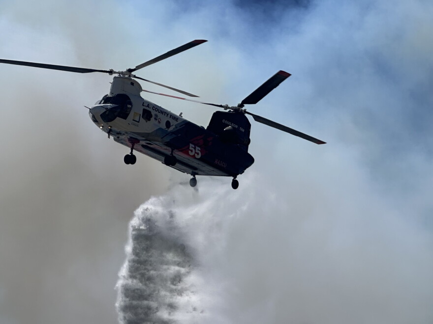 Firefighting efforts on the Sandy Fire include both ground and aerial support. Here, a helicopter drops fire retardant on May 18, 2026.