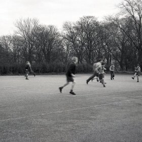 A group of schoolboys playing football outside on a large school playground, England, UK.