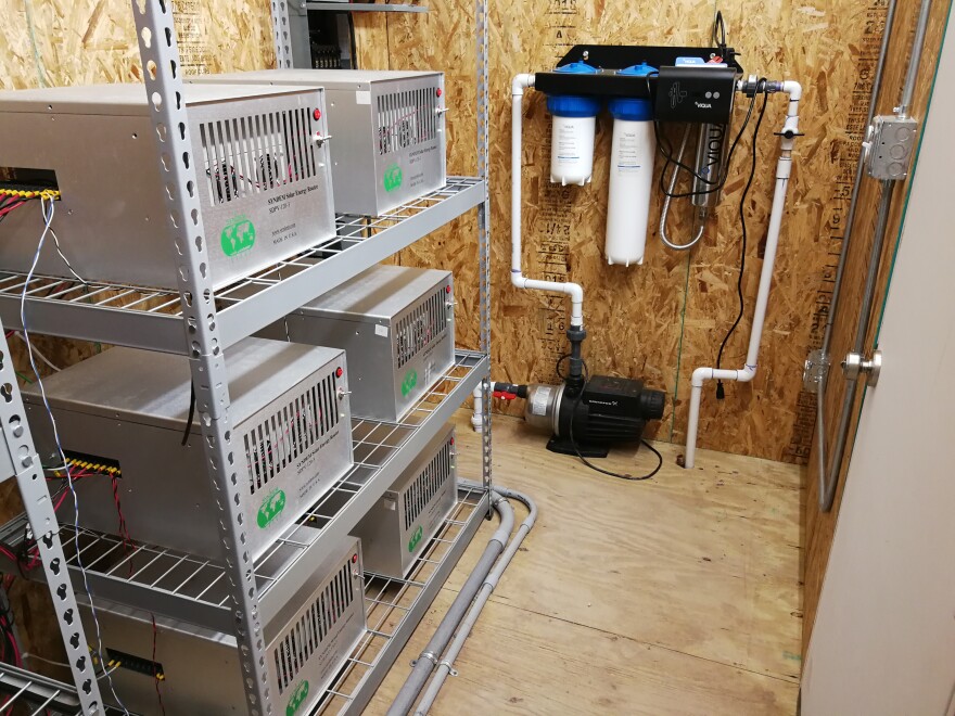 Inverters, batteries, and water filtration elements that make up the Home Utility Management System in a shed next to the home.