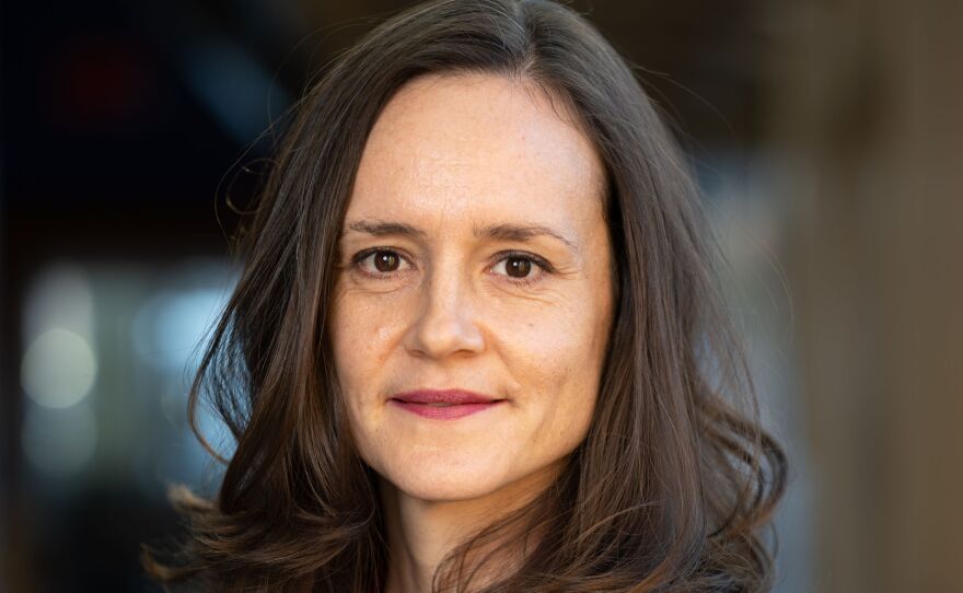 A woman with long dark hair is wearing a purple shirt.