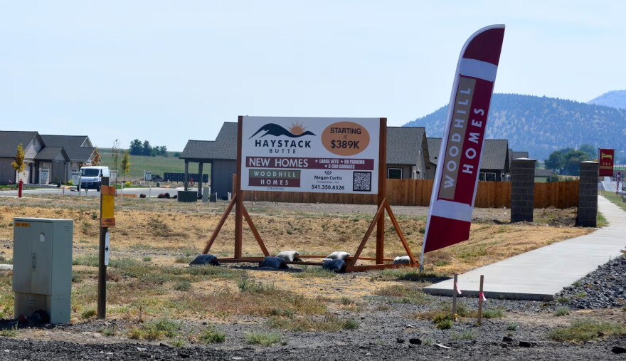 Signs for new homes in the foreground, with scrubland hills behind