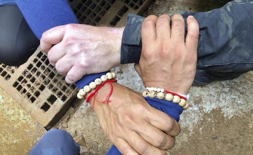 A photo released by the Thailand Navy SEAL Facebook page shows rescuers locking hands. Its caption says Thai and international rescuers are vowing to bring the boys home.