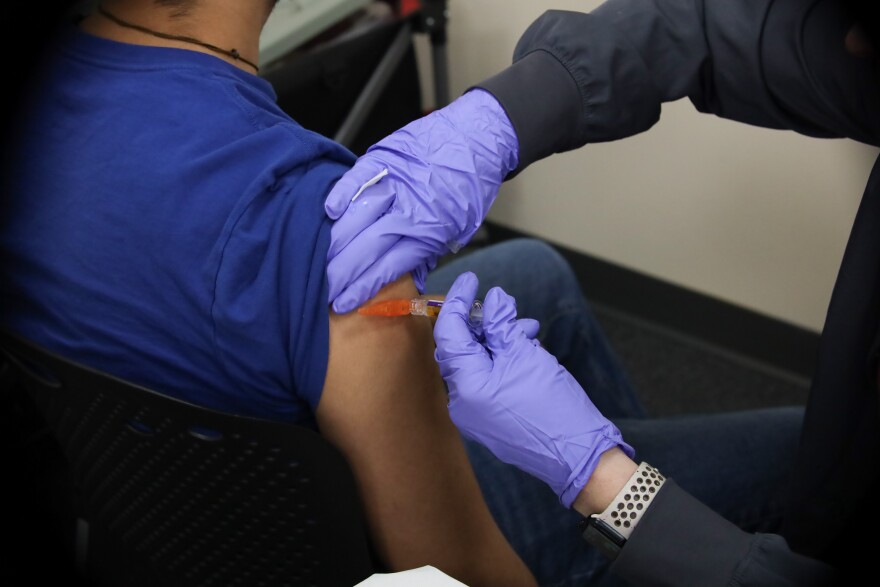 A nurse injects a vaccine into a man's arm. 