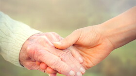 Elderly woman holding hands with young caretaker