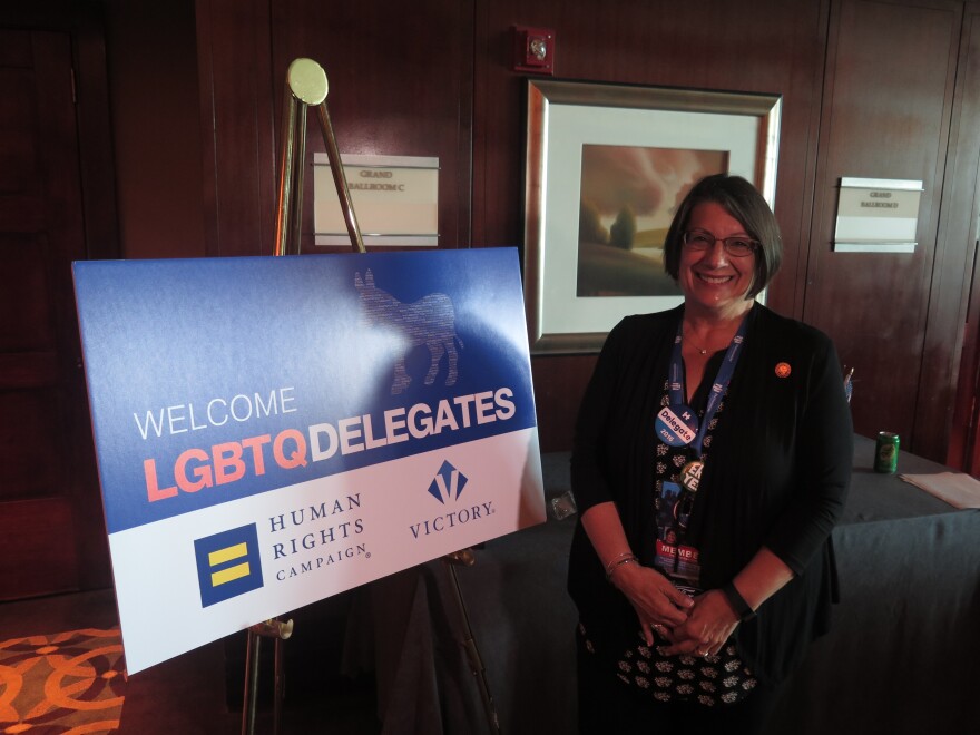 State Sen. Nickie Antonio stands beside a "Welcome LGBTQ Delegates" sign