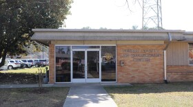 The Pender County Law Enforcement Center, a low brick building framed by magnolia trees, on a sunny day. 