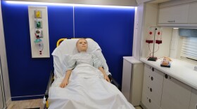 A medical mannequin rests in a hospital style bed inside ECPI University’s mobile simulation lab.