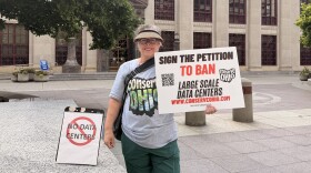 Conserve Ohio volunteer Kim Kinder-Smith stands outside Columbus City Hall on July 22, 2026 ahead of a public hearing on proposed data center regulations in the city. Kinder-Smith was gathering signatures for a measure to ban large data centers.