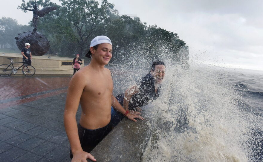 Connor Sidman and his mother Peggy Sidman get hit by a wave, as they take in the sights from the railing of Memorial Park in Jacksonville, Fla., Friday, Sept. 2, 2016. Hermine was downgraded to a tropical storm after it made landfall, as it moves over Georgia, but the U.S. National Hurricane Center says winds are increasing along the Southeast coast and flooding rains continue. (Bob Self/The Florida Times-Union via AP)