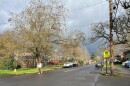 A person walks across a two-lane street near a pedestrian crossing sign