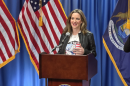 Michigan Secretary of State Jocelyn Benson, in a white shirt and black jacket, speaks at a lectern bearing the state of Michigan seal.