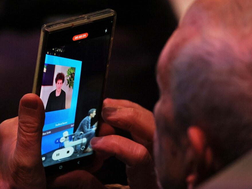 NEW YORK, NEW YORK - NOVEMBER 30: An attendee makes a video as FTX founder Sam Bankman-Fried speaks during the New York Times DealBook Summit in the Appel Room at the Jazz At Lincoln Center on November 30, 2022 in New York City. The New York Times held its first in-person DealBook Summit since the start of the coronavirus (COVID-19) pandemic with speakers from the worlds of financial services, technology, consumer goods, private investment, venture capital, banking, media, public relations, policy, government, and academia. (Photo by Michael M. Santiago/Getty Images)