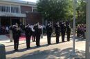 uniformed police officers with white gloves solute the flag in front of a brick building that is the Tallahassee Police Headquarters