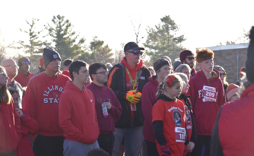 Parkside Junior High School cross-country coach Paul Bliss, center, wearing black, surrounded by PJHS students and other community members, listens during a Gift of Hope Organ and Tissue Donation Network flag-raising ceremony Saturday, Nov. 22, 2025, outside PJHS.